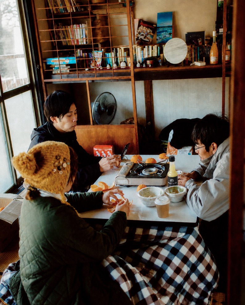 古民家の食卓に料理が並び、人が集まっている様子