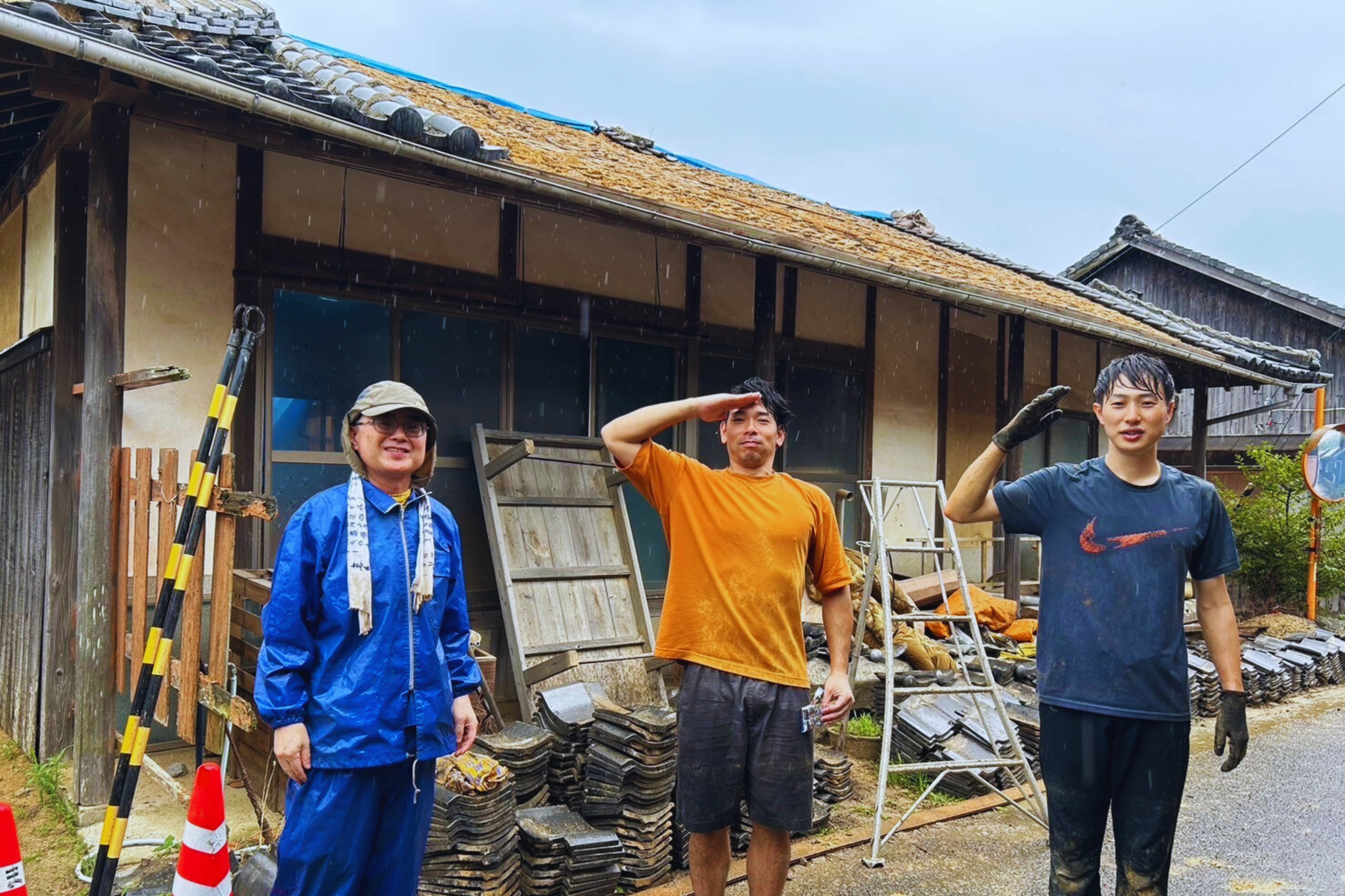 雨の中で古民家の屋根瓦を下ろした作業日の記念写真